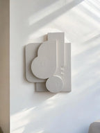 Abstract wall sculpture on a white wall with soft shadows